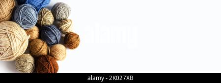 Blue, gray and brown balls of knitting thread on a light background for hobbies. Flat lay, banner Stock Photo