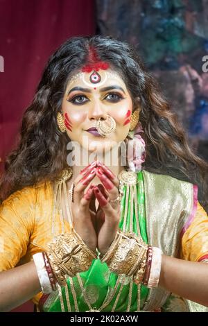 Beautiful Indian Woman dressed as Hindu Goddess Durga, looking away from camera. This is a representative concept of Agomoni Stock Photo