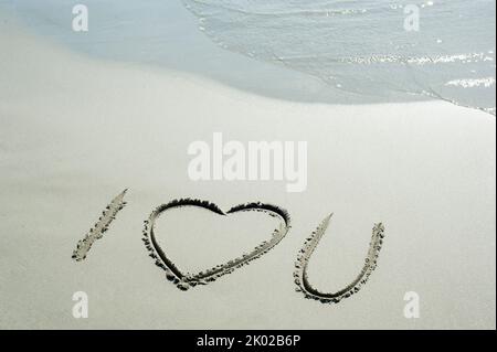 Concept or conceptual I love you text handwritten in sand on a beach with waves  in an exotic island for love, romance, summer, sea, ocean,  travel, h Stock Photo