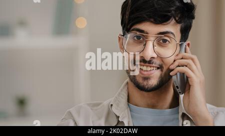 Portrait indoor male customer client business man guy boyfriend with glasses arab talking mobile phone answering call chatting friendly happy carefree Stock Photo