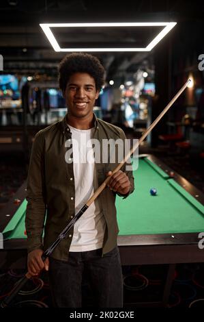 Portrait of young smiling man holding cue Stock Photo