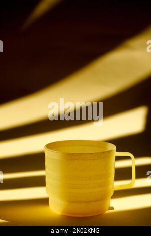 yellow plastic cup isolated on light and shadow Stock Photo