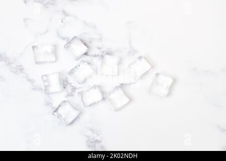 Ice cubes on a white and gray marble kitchen countertop in a top view Stock Photo