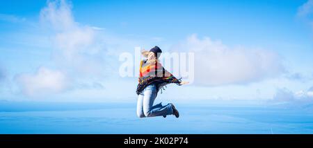 Woman overjoyed jumping crazy for happiness. Concept of freedom and joyful. Female people in leisure activity and fun with blue sky and ocean inbackground. Banner image of travel destination Stock Photo