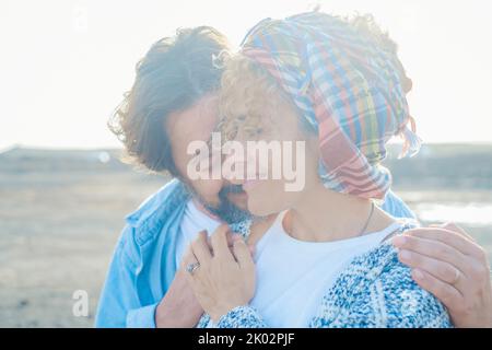 Careful young mature couple have care and touching with love each other. Romantic relationship with adult man and woman in outdoor leisure activity with bright light in background Stock Photo