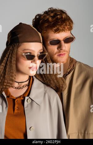 portrait of young stylish couple in autumnal outfits and sunglasses posing isolated on grey,stock image Stock Photo