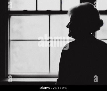 An elderly woman looking out of a window Stock Photo