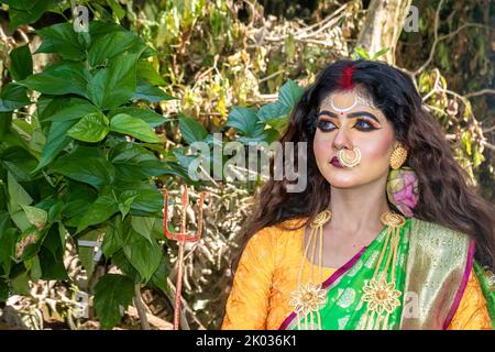 Concept Agomoni shoot with black haired Indian brunette  woman face with perfect makeup  and wearing jewelers with traditional dress like goddess . Stock Photo