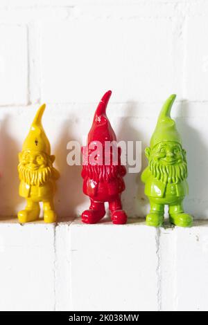 Three colorful dwarfs on a wall ledge Stock Photo