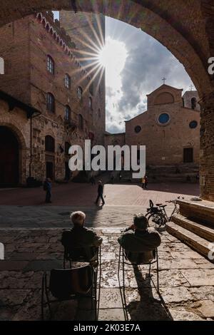 Two gentlemen with good view on the Piazza del Duomo, San Gimignano, Siena, Tuscany, Italy Stock Photo