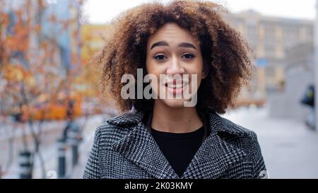 Young beautiful girl teenager millennial African American woman with curly hair stands in city on street suffers from seasonal allergy rhinitis runny Stock Photo