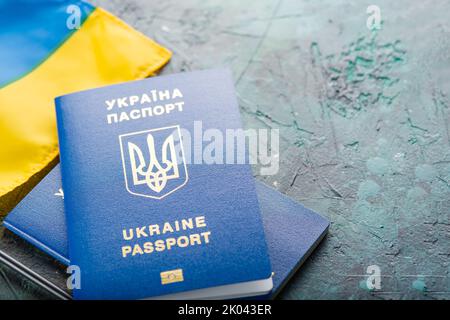 On a blue marble background, the flag of Ukraine and two biometric Ukrainian passports. Emigration, travel, business, Ukrainian refugees, Russian aggr Stock Photo