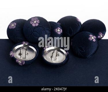 row of navy silk covered fabric buttons for handmade crafts in haberdashery sewing concept of hobbies on a white background Stock Photo