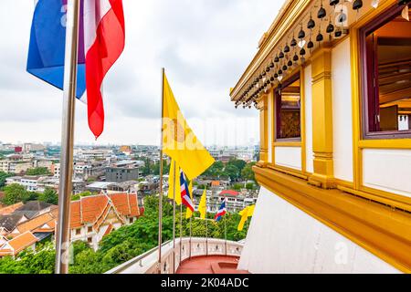 View from Wat Saket temple in Bangkok, Thailand. Detail of flags on top of Golden Mount. Thailand national flag with buddhism flag. In far cityscape o Stock Photo