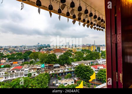 Look from window in Wak Saket temple (Golden mount) in Bangkok city, Thailand. Wooden ancient window with historic frame and heart bells shape. In far Stock Photo