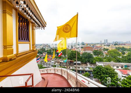 View from Wat Saket temple in Bangkok, Thailand. Detail of flags on top of Golden Mount. Thailand national flag with buddhism flag. In far cityscape o Stock Photo