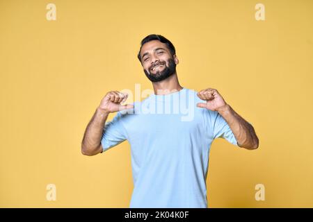 Smiling indian man standing isolated on yellow background pointing at himself. Stock Photo