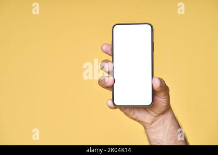 Male hand holding smartphone with white screen isolated on yellow background. Stock Photo