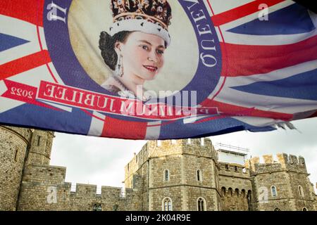 Windsor, UK. 9th September, 2022. A Union Jack bearing an image of Queen Elizabeth II is displayed opposite Windsor Castle. Queen Elizabeth II, the UK's longest-serving monarch, died at Balmoral aged 96 the previous day after a reign lasting 70 years. Credit: Mark Kerrison/Alamy Live News Stock Photo