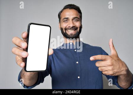 Happy indian business man pointing at mobile phone screen mockup. Stock Photo