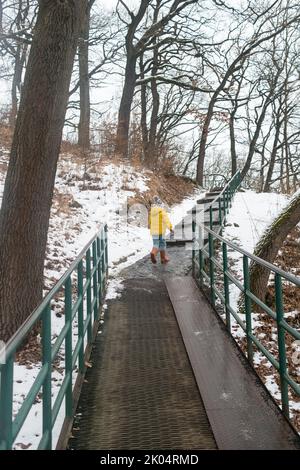 Child, boy running across the bridge in the city park. Winter holidays in the Slovakia town. Childhood. Stock Photo