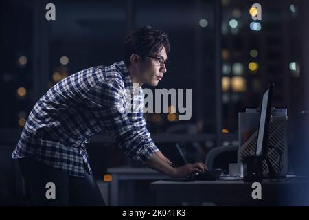 Chinese IT worker working in office at night Stock Photo