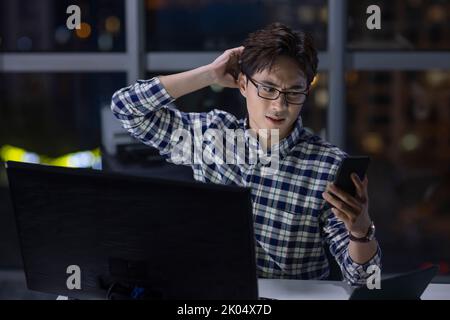Chinese IT worker working in office at night Stock Photo