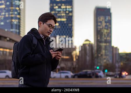 Chinese IT worker using smartphone outdoors Stock Photo