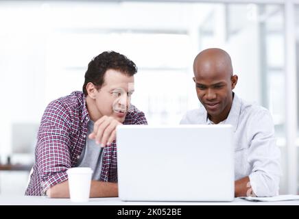 Using the latest design applications. Two professionals working together on a project on a laptop while sitting at a table. Stock Photo