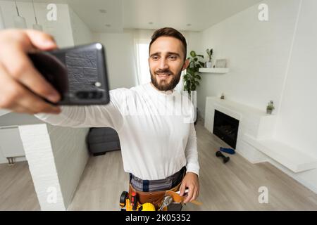 Smiling handsome young builder making selfie with mobile phone Stock Photo