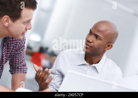Discussing a few design issues. Two professionals having a work discussion while seated at a desk. Stock Photo