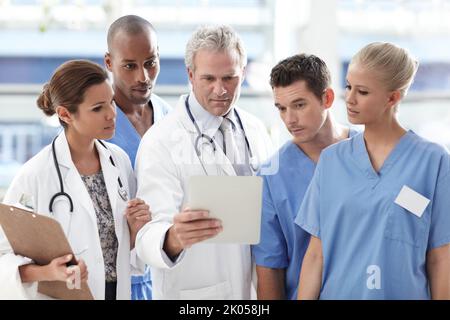 Preparing for procedure. Team of medical professionals looking at touchpad. Stock Photo