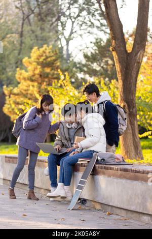 Happy Chinese college students using laptop on campus Stock Photo