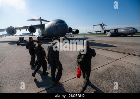 Airmen assigned to the 732nd Airlift Squadron and 111th Operations Group approach a C-17 Globemaster on Joint Base McGuire-Dix-Lakehurst, New Jersey, Aug. 24, 2022. Members of the 111th OG, Tactical Air Control Party specialists from the 148th Air Support Operations Squadron, and members of the 305th Air Mobility Wing and its associate reserve unit, the 514th Air Mobility Wing, took part in a multifaceted exercise that included the integration of an MQ-9 Reaper’s ability to support ground troops and coordinate support for a C-17 Globemaster III flying over hostile territory at training at Fort Stock Photo