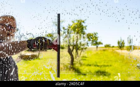 Man cleaning window with squeegee on a sunny Day Stock Photo