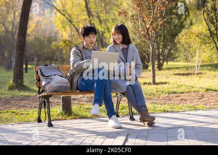 Happy Chinese college students using laptop on campus Stock Photo