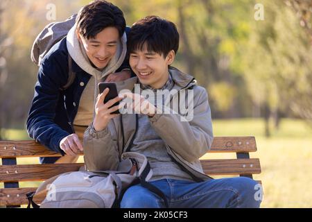 Happy Chinese college students using smart phone on campus Stock Photo