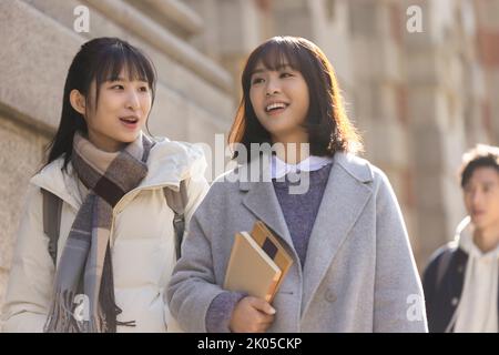 Happy Chinese college students walking on campus Stock Photo