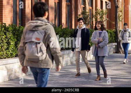 Happy Chinese college students walking on campus Stock Photo