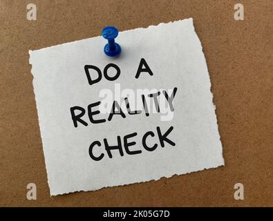 Do a reality check text on white notepad with wooden background. Reality check concept. Stock Photo