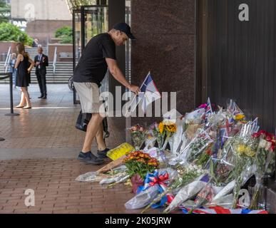 NEW YORK, N.Y. – September 9, 2022: A person leaves a flag at a tribute to Queen Elizabeth II near the British Consulate General in New York. Stock Photo