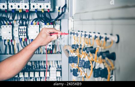 An electrical engineer is inspecting the operation of an electrical control cabinet. maintenance concept Stock Photo