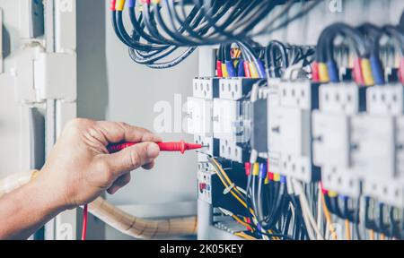 An electrical engineer is inspecting the operation of an electrical control cabinet. maintenance concept Stock Photo