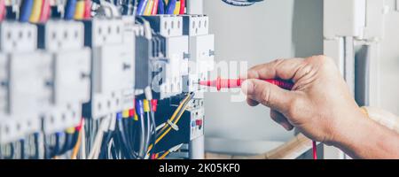 An electrical engineer is inspecting the operation of an electrical control cabinet. maintenance concept Stock Photo