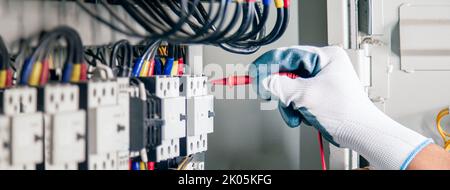 An electrical engineer is inspecting the operation of an electrical control cabinet. maintenance concept Stock Photo