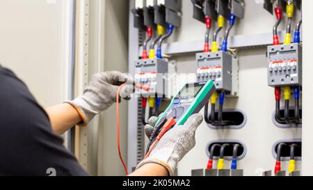 Engineers working to inspect and maintain electrical control cabinets. Stock Photo