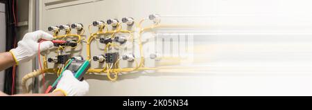 Electrical engineer tests the operation of the electric control cabinet on a regular basis for maintenance. Stock Photo