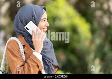Profile of muslim woman smiling while talking to the mobile Stock Photo