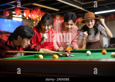 Happy young Chinese friends playing billiard together Stock Photo