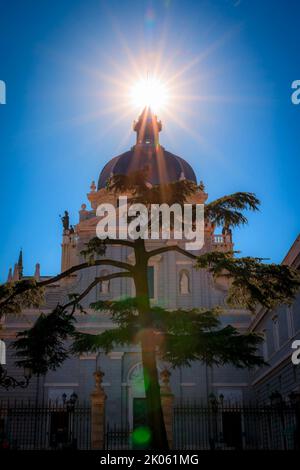 Sun setting in a sun burst behind the cross of the Cathedral of Our Lady of La Almudena in Madrid, Spain, consecrated by Pope John Paul II in 1993. Stock Photo